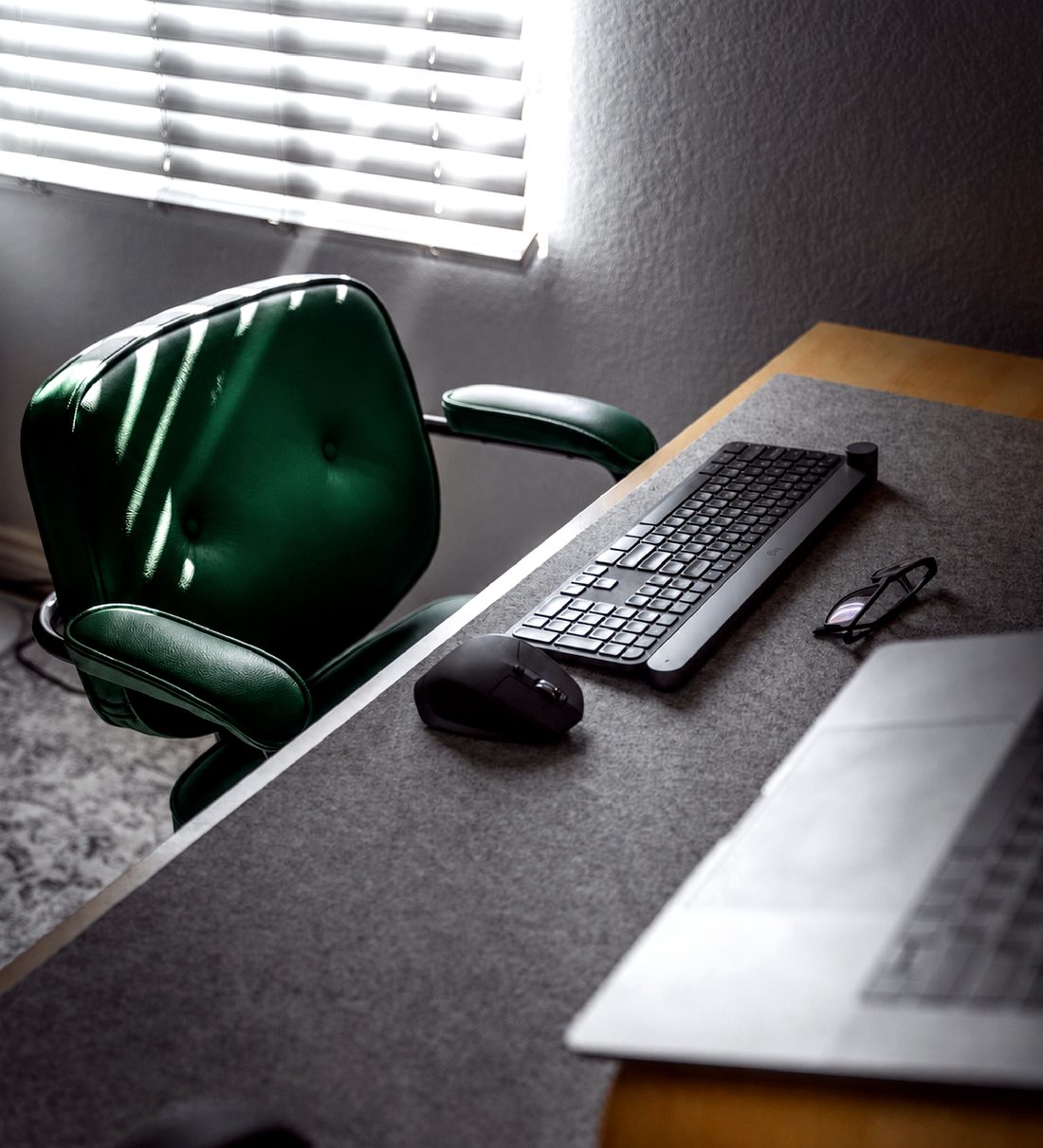 Executive desk with a green leather chair beside a sunlit window
